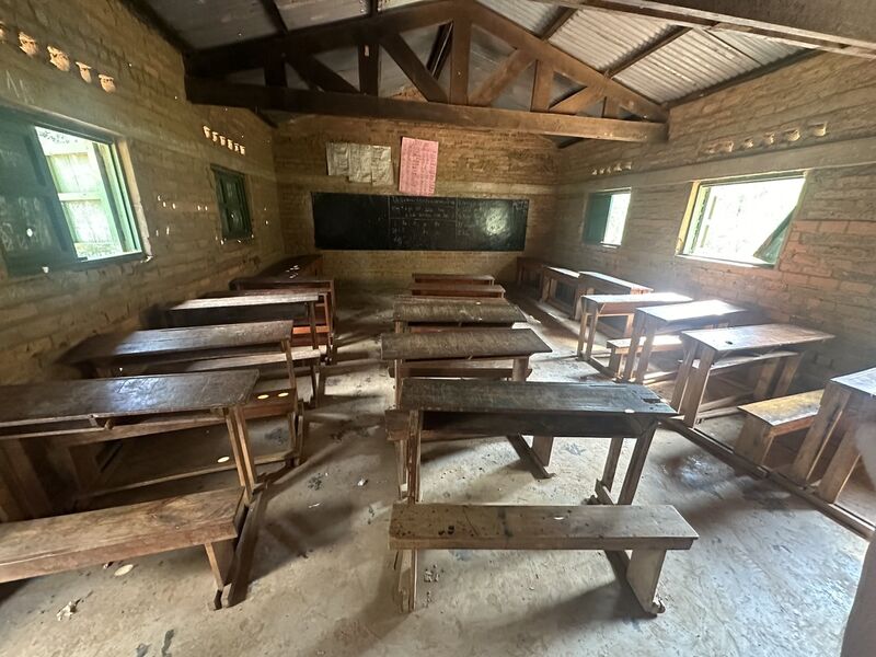 Klassenzimmer mit kaputten Bänken und Löchern in der Wand